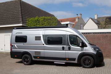 Pössl Roadcruiser huren in de kleur Eisengrau metallic lak. De schuifdeur staat open waardoor het lichte interieur te zien is.