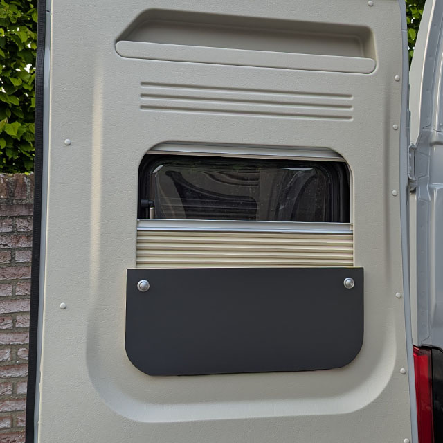 Een geopende deur van een Pössl Roadcruiser XL met het kussenbord van Campertrek in het raam geplaatst.