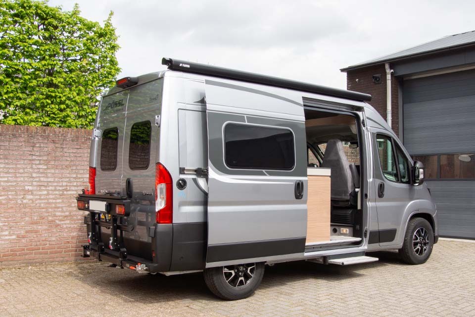 De bagageruimte van huurcamper Possl Roadcamp R buscamper is makkelijk toegankelijk doordat de fietsendrager weggedraaid kan worden van de deur