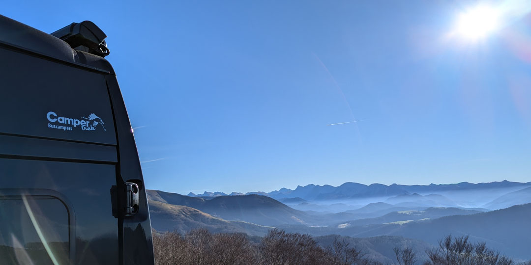 Het logo van Campertrek buscampers op de Pössl 2WinR buscamper met daarnaast uitzicht over de bergen in de Pyreneeën