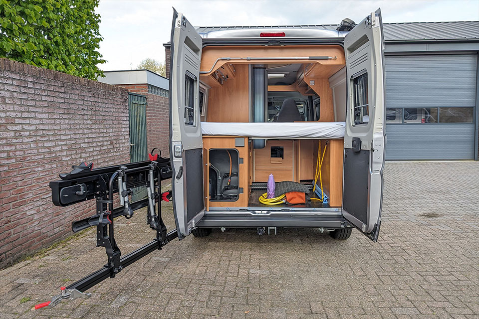Achterzijde van de Pössl 2Win R S met geopende achterdeuren en uitzwenkbare, opgeklapte Busbiker fietsendrager