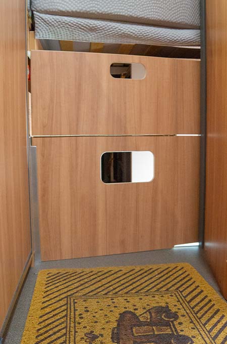 Het schot voor de bagageruimte onder het bed in de P&ouml;sslcamper is een klepkast geworden