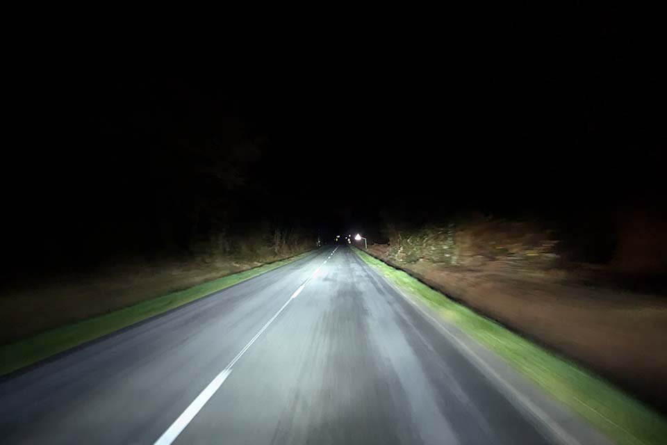 Met de buscamper rijden op een donkere weg zonder straatverlichting met alleen autolampen aan.