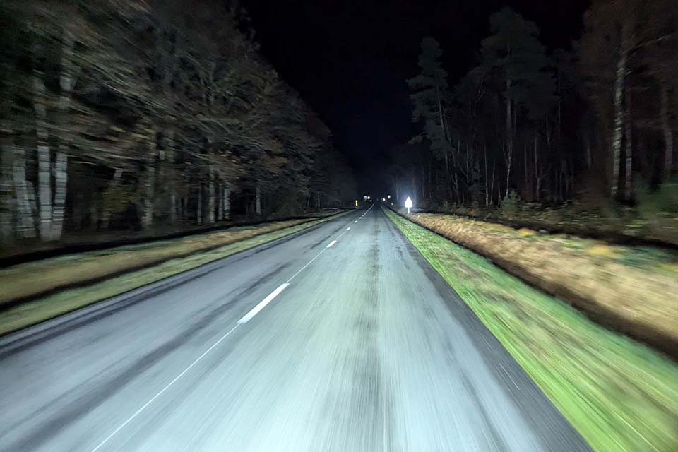 Rijden met de buscamper over een onverlichte weg door de bossen in Frankrijk met goed zicht door gebruik van verstralers.